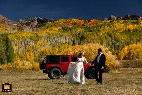 Kebler Pass, near Crested Butte, Colorado, is where the newlywed couple runs joyfully toward the bright sunshine after their wedding-day Jeep adventure through the vibrant fall foliage.